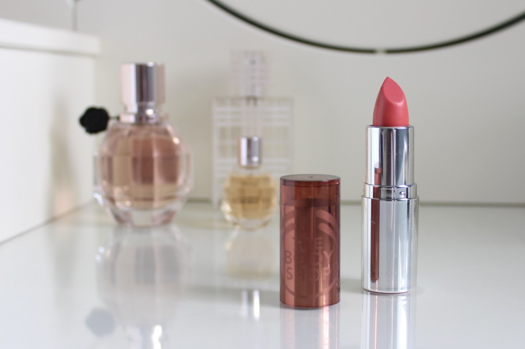 A picture of lipstick with perfume in the background